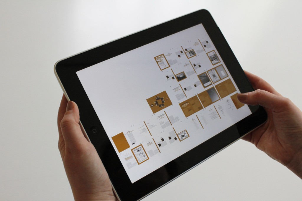 Mains tenant une tablette affichant une grille de pages d'une publication numérique