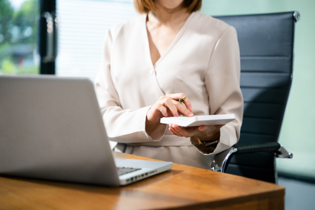 Professionnelle calculant des montants à relancer depuis son bureau